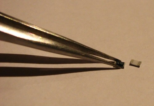 Tweezers picking up SMD resistors